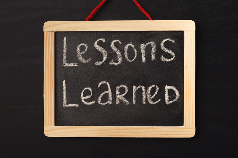 Word lessons learned written on miniature chalkboard in classroom against black background. Lessons, school, education concept.